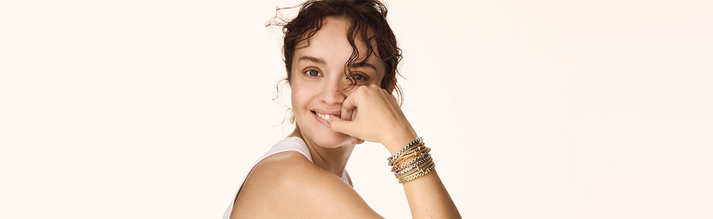 A girl model wearing Fope bracelet stackables on a beige background.
